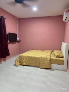 - une chambre avec un lit jaune dans un mur rose dans l'établissement D cateleya homestay, à Beranang