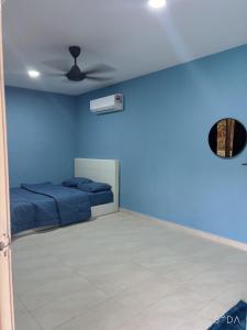 Cette chambre bleue comprend un lit et un ventilateur. dans l'établissement D cateleya homestay, à Beranang