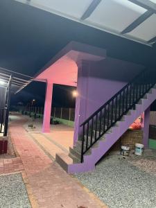 un escalier violet dans un bâtiment la nuit dans l'établissement D cateleya homestay, à Beranang
