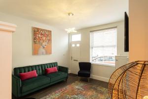 a living room with a green couch and a window at Sparkenhoe House in Hugglescote