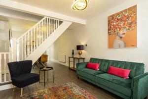 a living room with a green couch and a staircase at Sparkenhoe House in Hugglescote