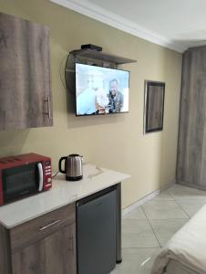 a kitchen with a microwave and a tv on the wall at Sunrise Boutique Hotel in eMalahleni