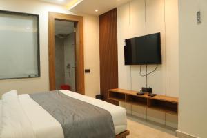 Schlafzimmer mit einem Bett und einem Flachbild-TV in der Unterkunft Hotel maxsun gwalior in Gwalior