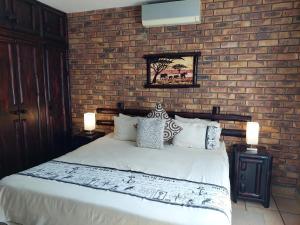 a bedroom with a bed with a brick wall at Khumbula iAfrica 2 in Marloth Park