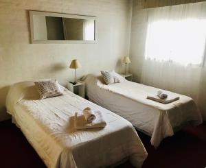 Habitación con 2 camas, toallas y ventana. en Casa Patagonica en Puerto Madryn