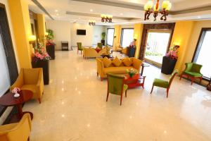 a lobby with yellow couches and green chairs at Grand Serenaa Hotel & Resorts, Auroville in Auroville