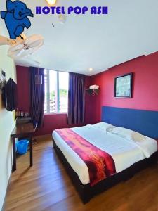 a bedroom with a bed with a red wall at HOTEL POP ASH in Brinchang