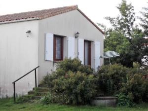 uma pequena casa branca com escadas e um guarda-chuva em EN PLEINE VERDURE AU CALME NON LOIN DU CENTREVILLE em La Tranche-sur-Mer