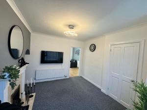 a hallway with a flat screen tv and a mirror at Home In Coventry in Coventry