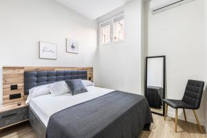 a bedroom with a large bed and a black chair at Apartamentos a 5 minutos del centro de Madrid 4P in Madrid