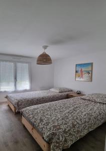 a bedroom with two beds and a pendant light at Magnifique appart à Sanguinet à 400 m du lac in Sanguinet