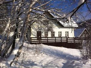 ein weißes Haus mit einem Zaun im Schnee in der Unterkunft Holiday home in a quiet authentic mountain village with a view of the surrounding hills in Zlatá Olešnice