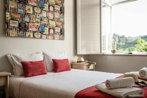 een slaapkamer met een groot wit bed met rode kussens bij Alojamento Casa do Rio in Peso da Régua