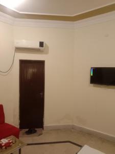 ein Wohnzimmer mit einem roten Sofa und einem Flachbild-TV an der Wand in der Unterkunft Regal Guest House in Bahawalpur