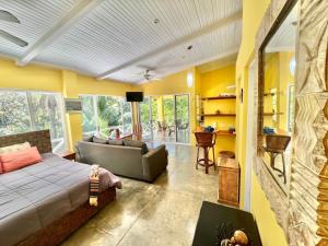 ein Schlafzimmer mit einem Bett und ein Wohnzimmer mit gelben Wänden in der Unterkunft Casa Amable by Ronnys Place in Manuel Antonio
