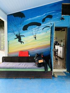 ein Schlafzimmer mit einem Bett mit an der Wand gemalten Fallschirmen in der Unterkunft Casa Amable by Ronnys Place in Manuel Antonio