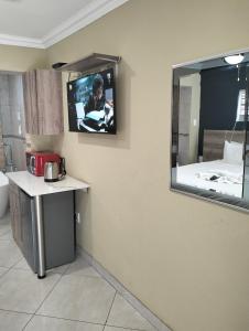 a room with a tv on a wall with a mirror at Sunrise Boutique Hotel in eMalahleni