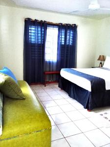 1 dormitorio con cama, sofá y ventana en BONI CHATEAU VACATION SPOT is a One Bedroom Self-contained Apartment For Travelers Needing To Be In Tune With Nature, en Discovery Bay