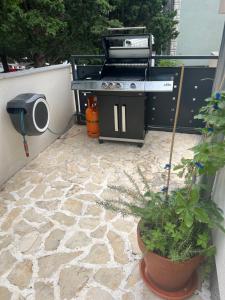 a grill and a potted plant on a patio at Sunset Huus in Starigrad-Paklenica