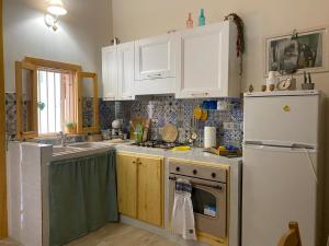 a kitchen with white cabinets and a white refrigerator at Residenza Ronna Razia in Avola
