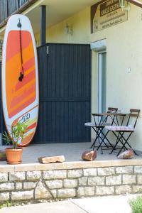 Una tabla de surf junto a una mesa y una mesa de picnic. en Kincső Vendégház Siófok by NeWave Apartments, en Siófok