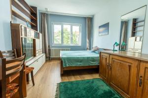 een slaapkamer met een bed, een bureau en een raam bij 3-BR Central Residence in Sofia