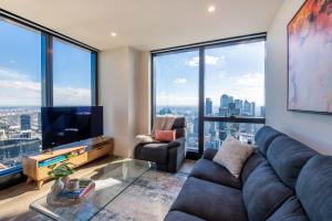 uma sala de estar com um sofá e uma televisão e janelas grandes em Stunning Apartment on Lvl 66 Car Park Pool Gym em Melbourne