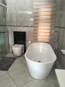 a bathroom with a white tub and a toilet at Sunrise Boutique Hotel in eMalahleni