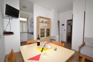 ein Esszimmer mit einem Tisch und einer Flasche Wein in der Unterkunft Comfy flat 80m from the beach - Beahost in Bibione