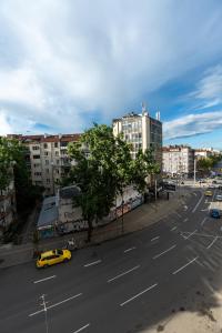 een uitzicht op een straat met een gele taxi bij 3-BR Central Residence in Sofia