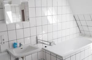 Un baño blanco con lavabo y espejo. en home2stay Worker House Feldstetten Kitchen,Wifi,Smart TV Parking ***, en Laichingen 11 fotos más