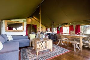 una sala de estar con sofá y mesa en una tienda en Safari Tent 1 With Log Burning Tub At Tapnell Farm, en Yarmouth