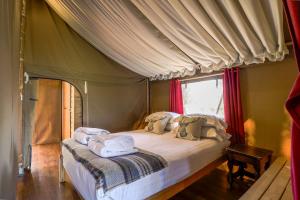 1 dormitorio con cama con dosel y toallas. en Safari Tent 1 With Log Burning Tub At Tapnell Farm, en Yarmouth