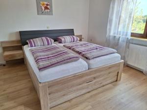 a bedroom with a wooden bed with two pillows at Haus Bergblick Bay. Wald in Prackenbach