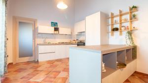 una cucina con armadietti bianchi e pavimento piastrellato di Welcomely - Domo Mea a Càbras