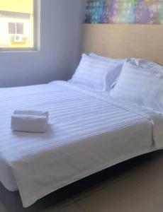 a bed with white sheets and a box on it at Living At DSulaiman Hotel in Kuala Lumpur