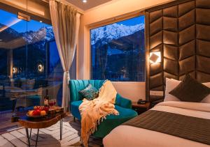 a bedroom with a bed and a chair and a window at Moustache Manali in Manāli