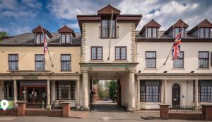 un grand bâtiment blanc avec deux drapeaux devant lui dans l'établissement Bridge House Hotel, à Birmingham