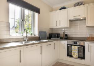 a kitchen with white cabinets and a sink and a microwave at The Haven in Snape