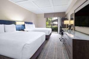 a hotel room with two beds and a flat screen tv at Wyndham Boca Raton Hotel in Boca Raton