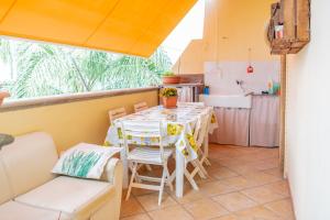 Una habitación con una mesa y sillas y una cocina. en Appartamento Solatio con 3 camere a Presicce, en Presicce