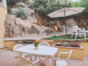 a table and chairs and an umbrella on a patio at Domus DELEDDA 'Sole' in Posada