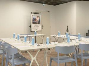 una habitación con mesas y sillas y botellas de agua. en ibis styles Dax Centre, en Dax