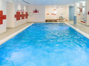 a large swimming pool with blue water in a room at Novotel Milton Keynes in Milton Keynes