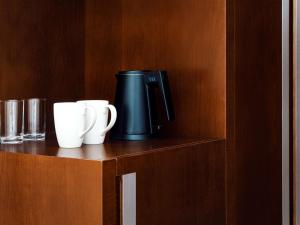 a coffee maker and two cups sitting on a shelf at Novotel Dubai Al Barsha in Dubai