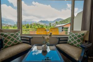 een woonkamer met 2 stoelen en een glazen tafel bij Kamal Residency By Revanta Hospitality Mcleodganj in Dharamshala