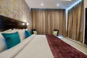 een hotelkamer met een groot bed met blauwe kussens bij Kamal Residency By Revanta Hospitality Mcleodganj in Dharamshala