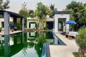 a house with a pool and a table and an umbrella at Thai Good Arts Resort in Chiang Mai