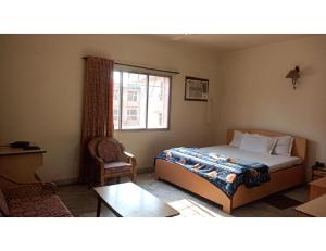 Hotel City Centre, Agartala في آغارتالا: غرفة نوم بسرير وطاولة ونافذة
