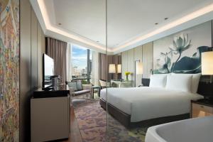 バンコクにあるサイアム ケンピンスキー ホテル バンコク - SHA Extra Plus Certifiedのベッドとデスクが備わるホテルルームです。
